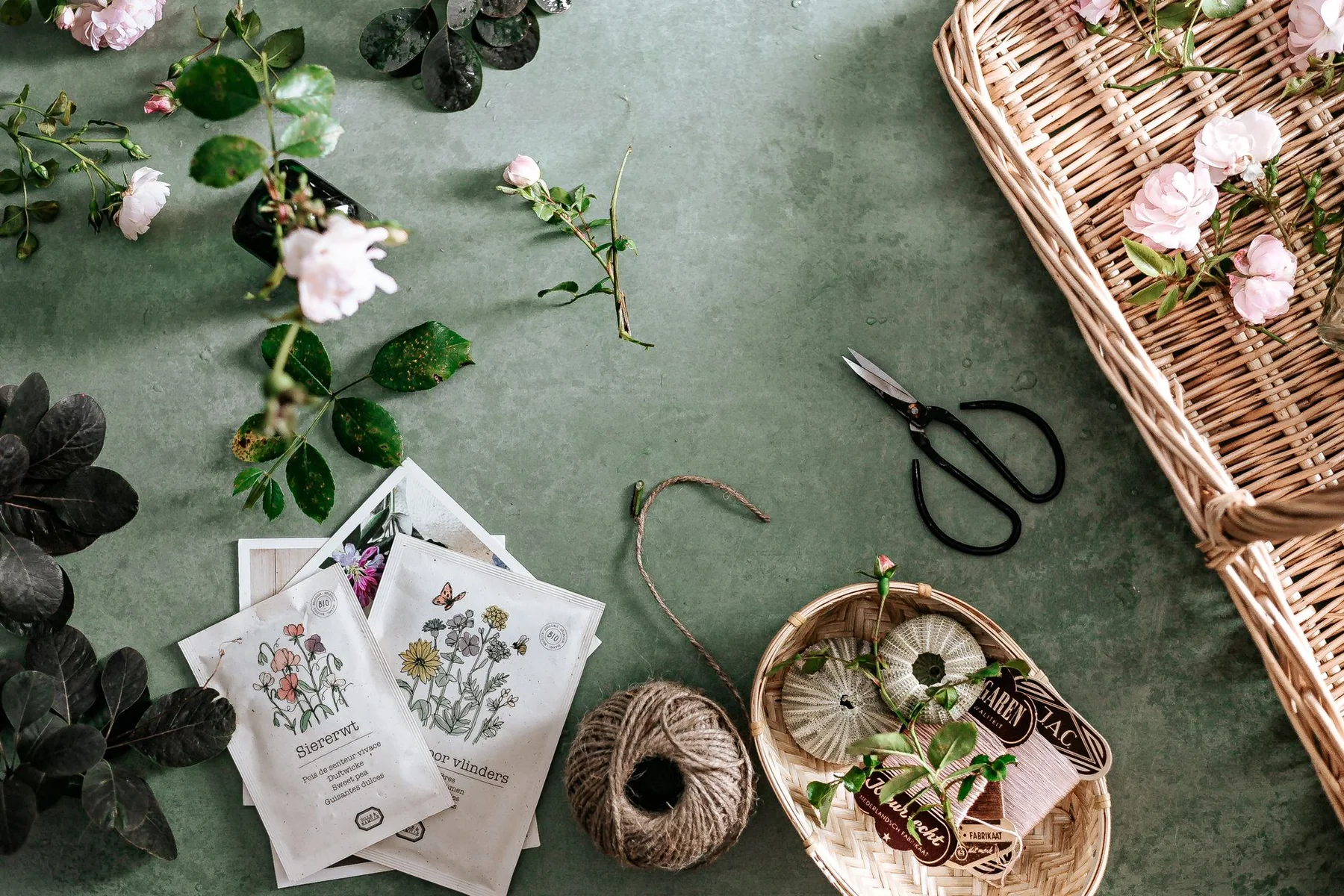 Garden tools, seed packets, and flowers are arranged on a green background.